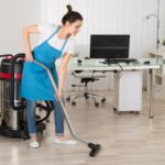Choosing a Commercial Cleaning Company in Winnipeg: 6 Key Checks 4 A cleaner in a blue apron vacuuming indoor floors with a wet-dry vacuum, supporting thorough post-construction cleaning in Manitoba.