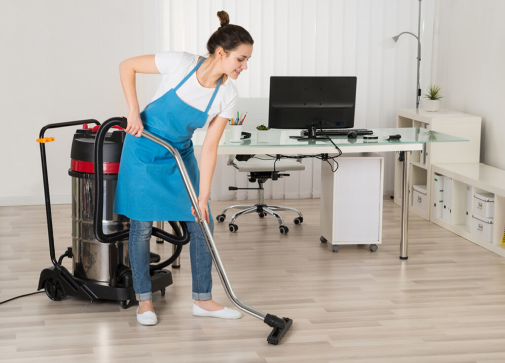 Choosing a Commercial Cleaning Company in Winnipeg: 6 Key Checks 1 A cleaner in a blue apron vacuuming indoor floors with a wet-dry vacuum, supporting thorough post-construction cleaning in Manitoba.